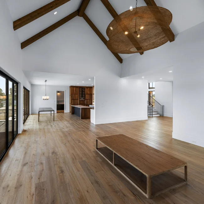 Open living room with timber beams and walnut coffee table in Edgewater Estate, a custom home by Mike Stevens Homes