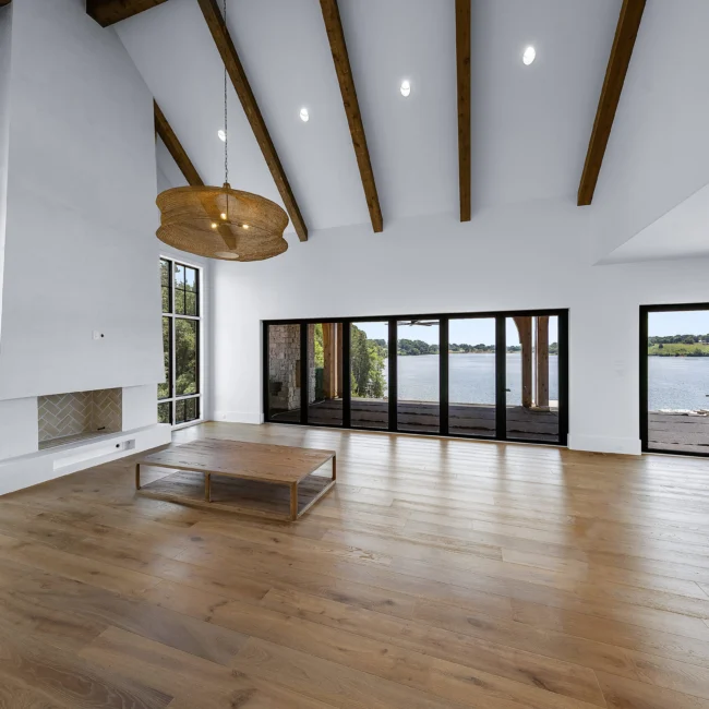 Vaulted great room with lake-view sliding doors and coffee table in Edgewater Estate, a custom home by Mike Stevens Homes