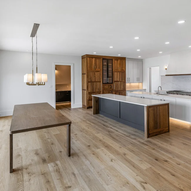Kitchen with walnut pantry tower, gray island and dining table in Edgewater Estate, a custom home by Mike Stevens Homes