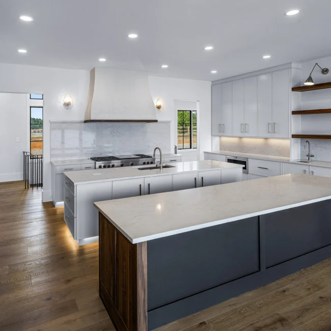 White kitchen with marble-look backsplash and under-cabinet lights in Edgewater Estate, a custom home by Mike Stevens Homes