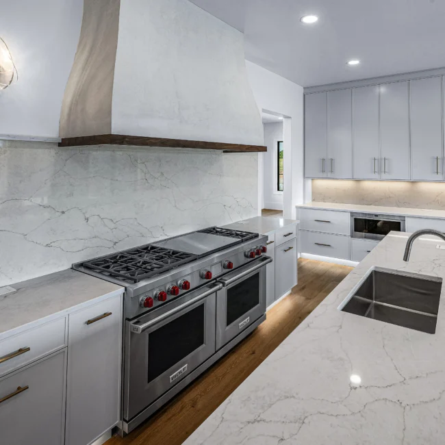 Kitchen with marble backsplash, red-knob pro range and quartz in Edgewater Estate, a custom home by Mike Stevens Homes