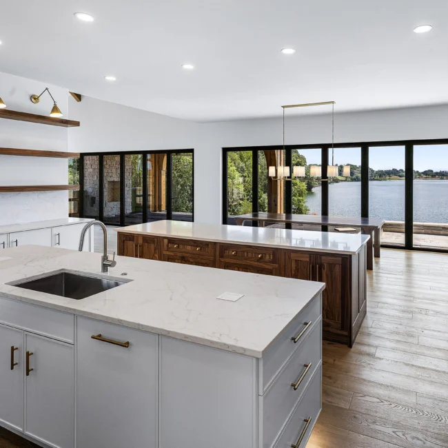 Kitchen island with sink facing lake-view windows and walnut end in Edgewater Estate, a custom home by Mike Stevens Homes
