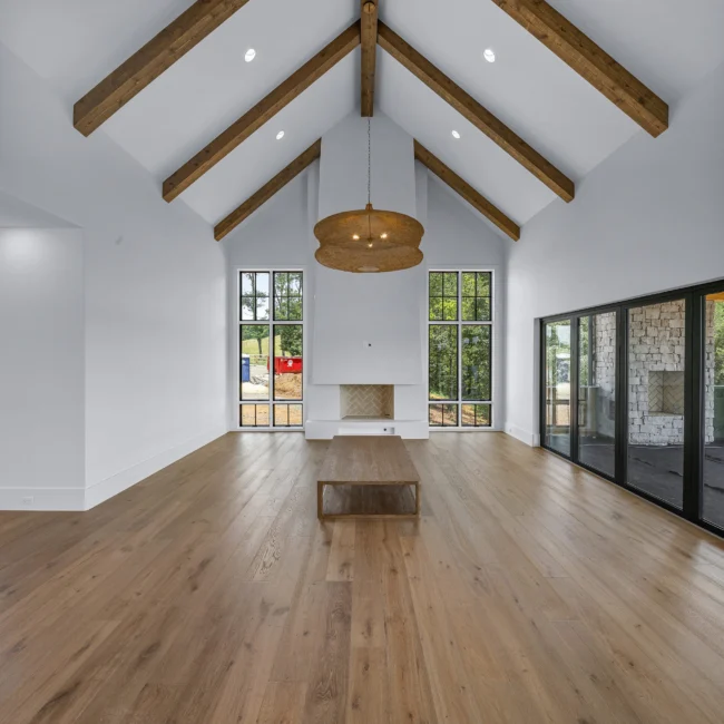 Two-story great room with beamed ceiling, fireplace and tall windows in Edgewater Estate, a custom home by Mike Stevens Homes