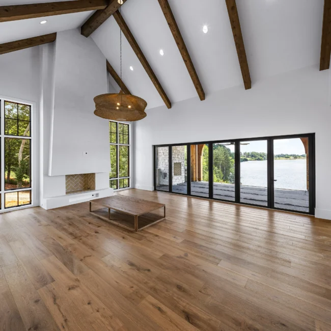 Great room with beamed ceiling and black-framed doors to lake deck in Edgewater Estate, a custom home by Mike Stevens Homes