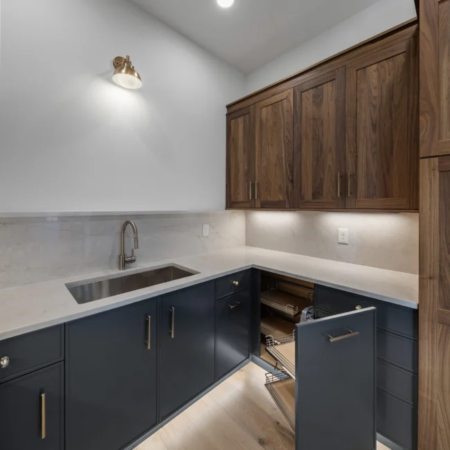 Prep kitchen with walnut uppers, gray bases and pull-out drawers in Edgewater Estate, a custom home by Mike Stevens Homes