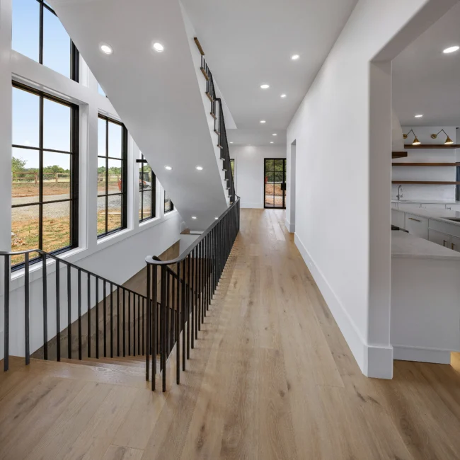 Upper hall with black iron railing and wood floors beside stairs in Edgewater Estate, a custom home by Mike Stevens Homes
