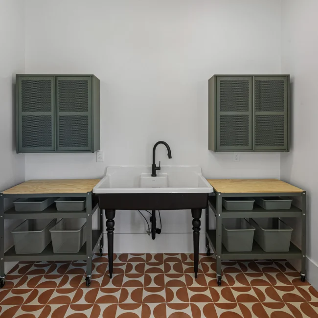 Utility room with sage cabinets, farmhouse sink and patterned tile in Edgewater Estate, a custom home by Mike Stevens Homes