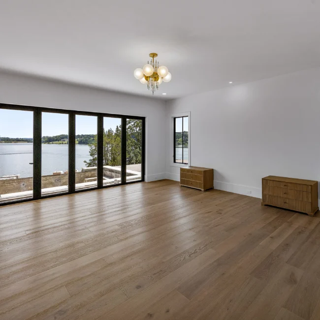 Living room with lake-view glass doors and a chandelier in Edgewater Estate, a custom home by Mike Stevens Homes