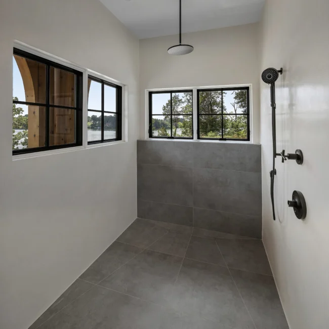 Walk-in shower with gray tile, black fixtures and arched windows in Edgewater Estate, a custom home by Mike Stevens Homes