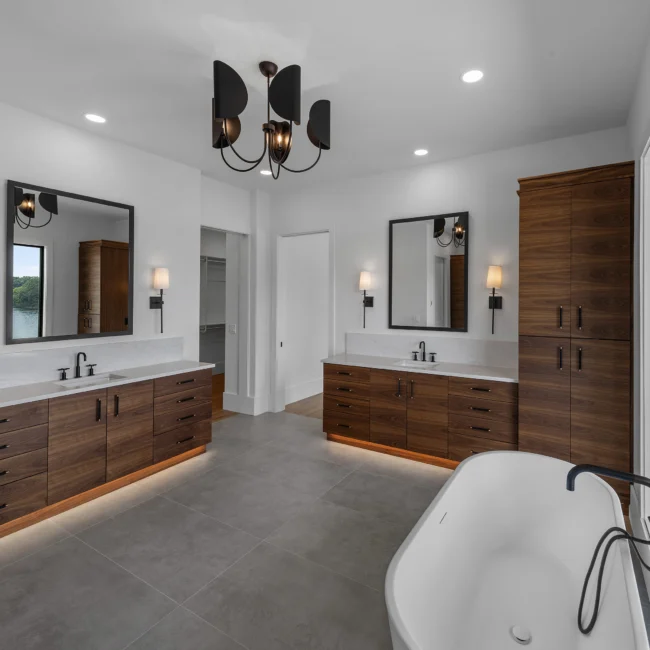 Primary bath with walnut double vanity and freestanding tub in Edgewater Estate, a custom home by Mike Stevens Homes