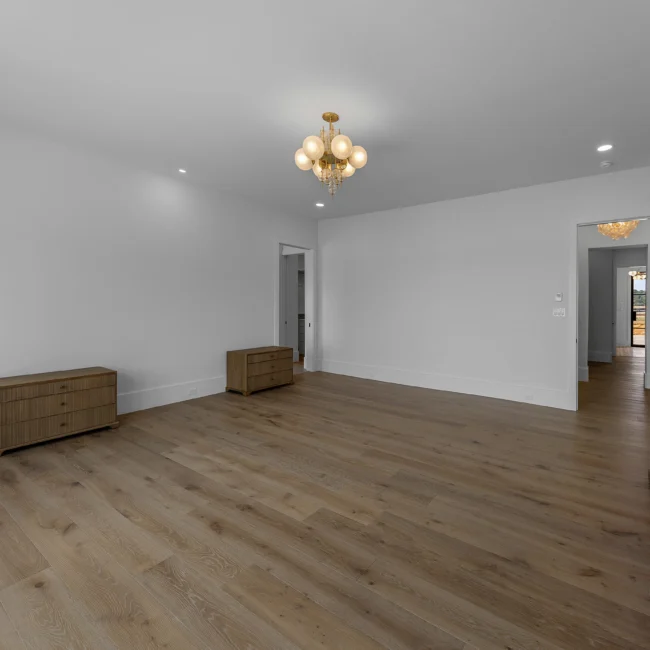Empty bedroom with wood floors, chandelier and hallway view in Edgewater Estate, a custom home by Mike Stevens Homes