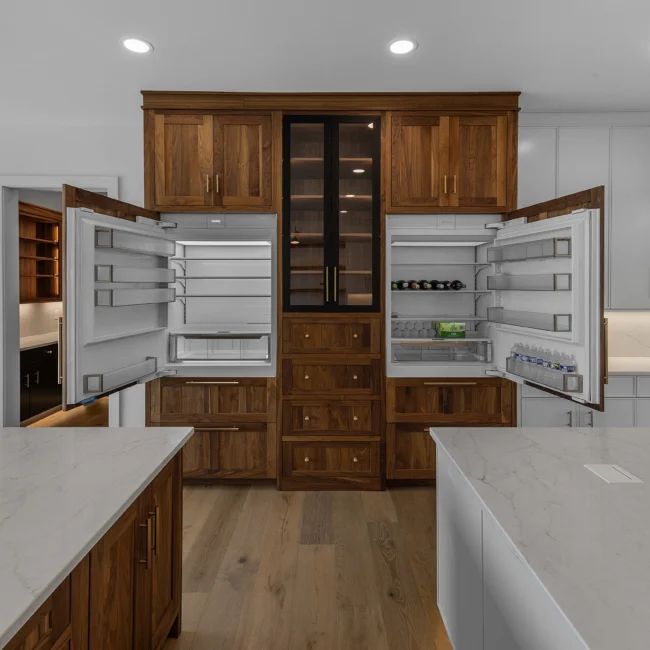 Walnut built-in pantry wall with glass cabinets and fridge drawers in Edgewater Estate, a custom home by Mike Stevens Homes