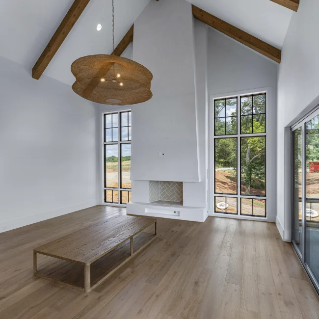 Great room with pendant light, wood floors and tall windows in Edgewater Estate, a custom home by Mike Stevens Homes