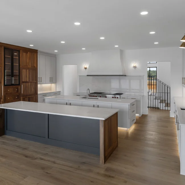 Kitchen with gray island, white hood and walnut pantry wall in Edgewater Estate, a custom home by Mike Stevens Homes