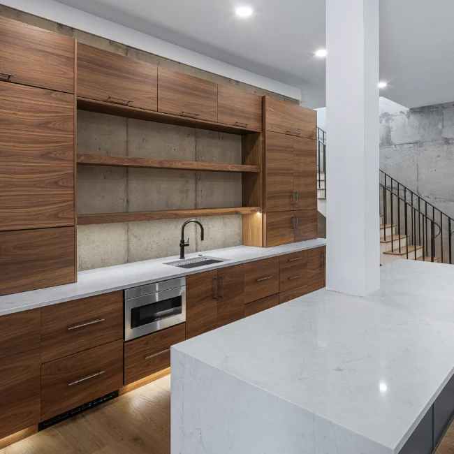 Walnut kitchen with floating shelves, waterfall island and staircase in Edgewater Estate, a custom home by Mike Stevens Homes