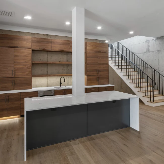 Walnut kitchen with gray island, floating shelves and staircase in Edgewater Estate, a custom home by Mike Stevens Homes