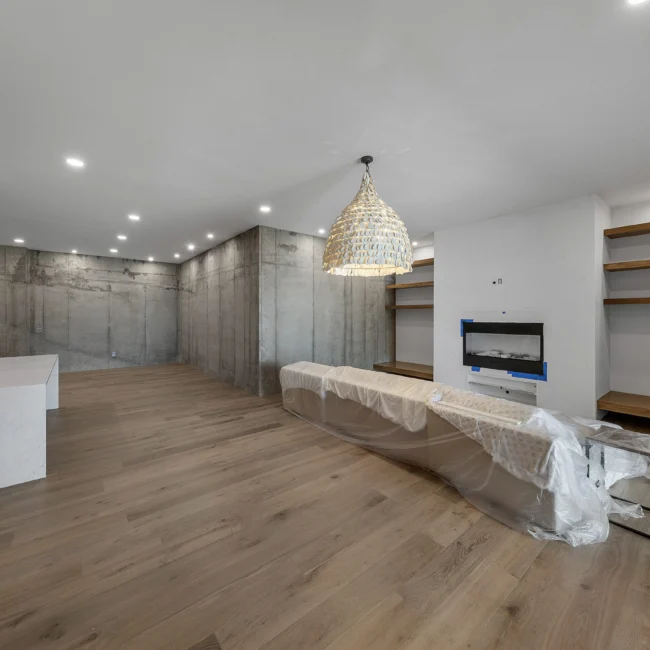 Lower-level living room with concrete wall and linear fireplace in Edgewater Estate, a custom home by Mike Stevens Homes