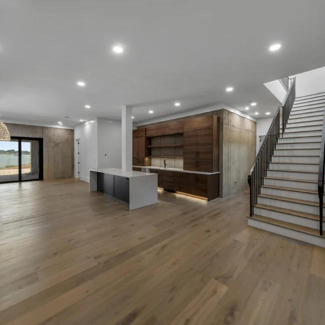 Lower-level open kitchen with walnut cabinets and concrete walls in Edgewater Estate, a custom home by Mike Stevens Homes