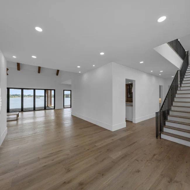 Open hall with recessed lights, black stair railing and wood floors in Edgewater Estate, a custom home by Mike Stevens Homes