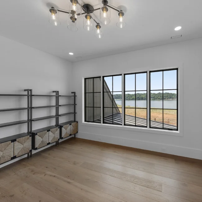 Room with black-framed windows over countryside and shelving in Edgewater Estate, a custom home by Mike Stevens Homes