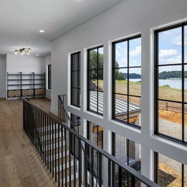 Upper gallery with black-framed windows and iron railing in Edgewater Estate, a custom home by Mike Stevens Homes