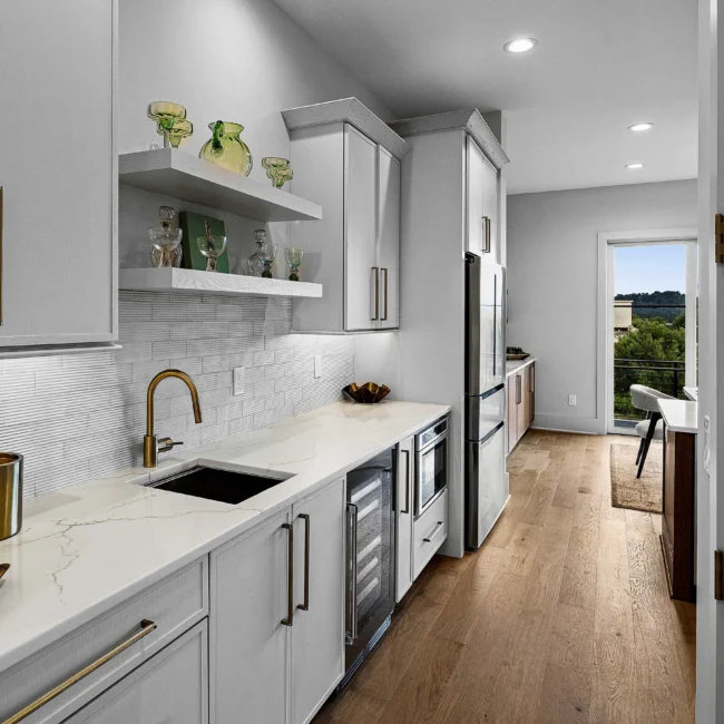 Kitchen with white shaker cabinets, brass pulls and subway backsplash in The Terrace by Mike Stevens Homes