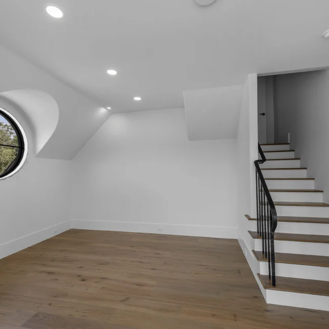 Bonus room with round window, sloped ceiling and staircase in Edgewater Estate, a custom home by Mike Stevens Homes