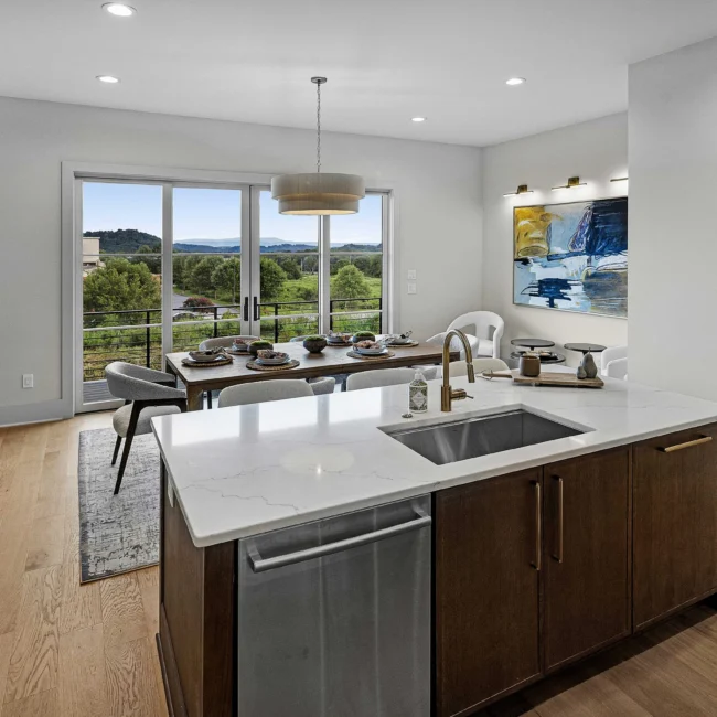Kitchen island with quartz top, undermount sink and dining view in The Terrace by Mike Stevens Homes