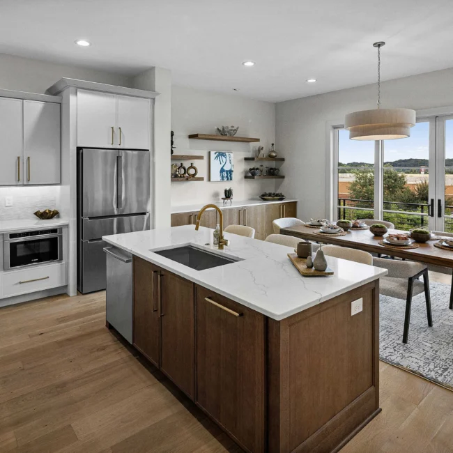 Kitchen with brown island base, quartz counter and stainless fridge in The Terrace by Mike Stevens Homes