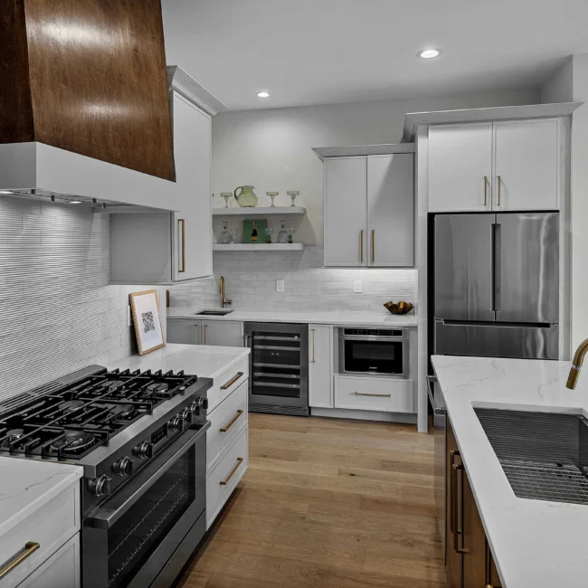 Kitchen with gas range, white cabinets and stainless refrigerator in The Terrace by Mike Stevens Homes