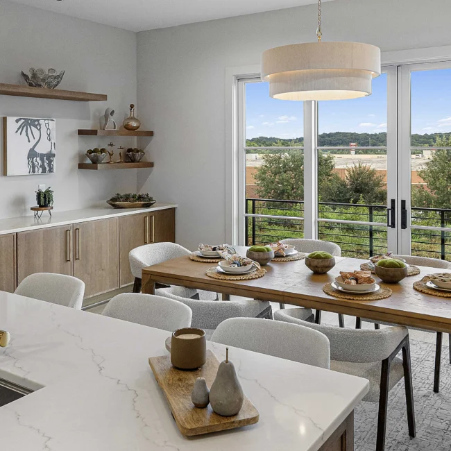 Dining room with wood table, white chairs and sliding doors to balcony in The Terrace by Mike Stevens Homes