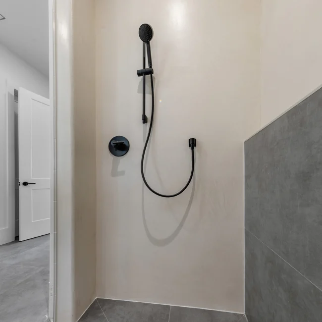 Walk-in shower with matte black handheld fixture and gray tile in Edgewater Estate, a custom home by Mike Stevens Homes