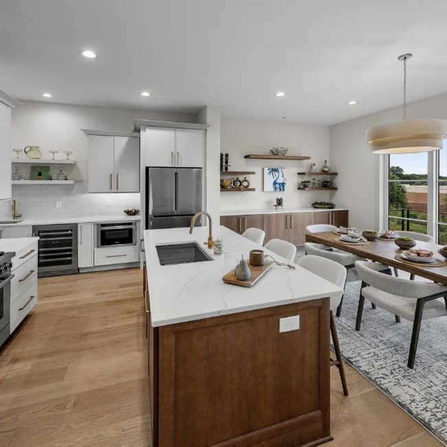 Kitchen with white cabinets, island and dining nook beyond in The Terrace by Mike Stevens Homes