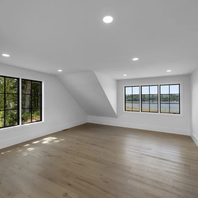 Empty room with sloped ceiling and black-framed windows in Edgewater Estate, a custom home by Mike Stevens Homes