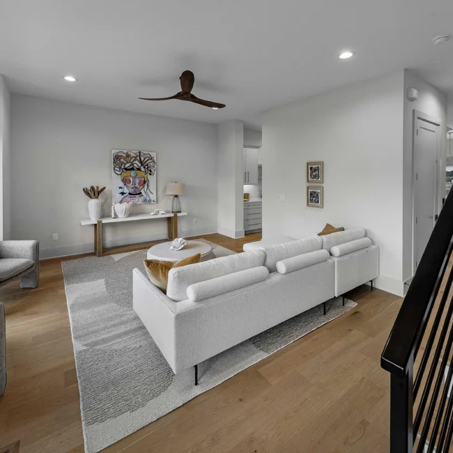 Living room with white sectional, console table and framed art in The Terrace by Mike Stevens Homes