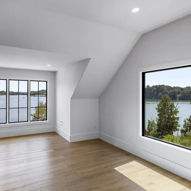 Empty room with lake-view window in an angled dormer in Edgewater Estate, a custom home by Mike Stevens Homes