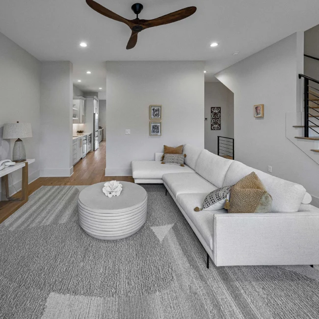Living room with curved white sectional and round coffee table in The Terrace by Mike Stevens Homes