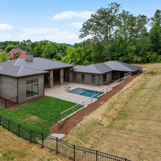 Aerial of the rear patio and pool wrapped by bronze hip roofs at Modern Prairie by Mike Stevens Homes