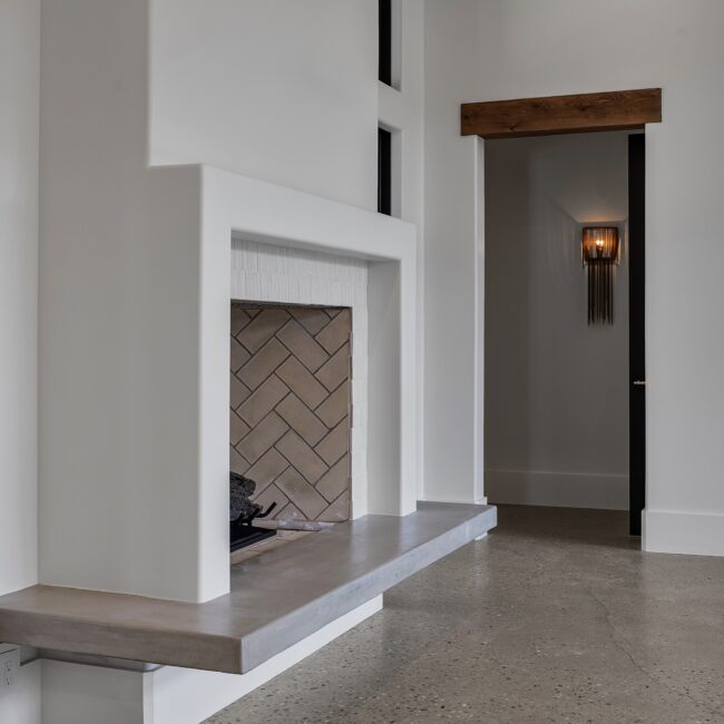 Fireplace with herringbone firebox and floating concrete hearth in Modern Prairie by Mike Stevens Homes
