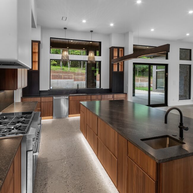 Walnut kitchen with dark island and polished concrete floors in Modern Prairie by Mike Stevens Homes