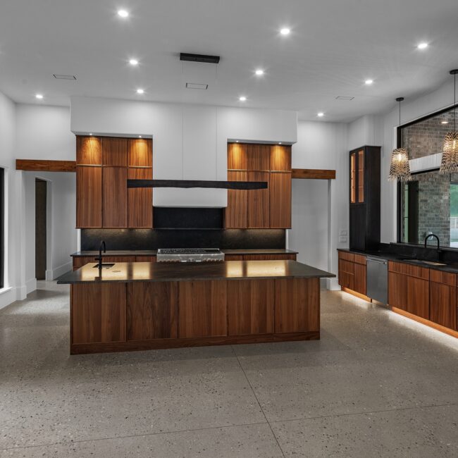 Kitchen with walnut island and glass-front uppers open to the living area in Modern Prairie by Mike Stevens Homes