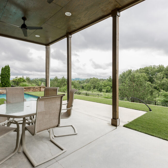 Lower covered patio overlooking the pool and valley at Rockport Gray Farmhouse by Mike Stevens Homes