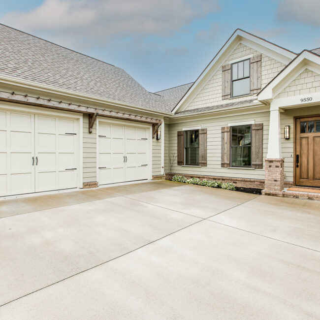 Brick-based porch columns and carriage garage doors under a cedar pergola at Rockport Gray Farmhouse by Mike Stevens Homes