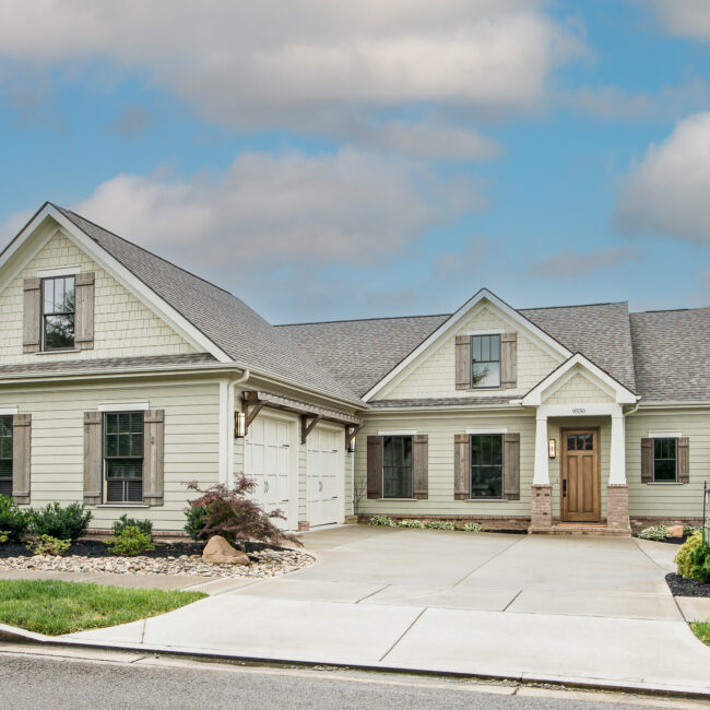 Front of Rockport Gray Farmhouse with shingled gables, cedar shutters and a stained wood front door, by Mike Stevens Homes