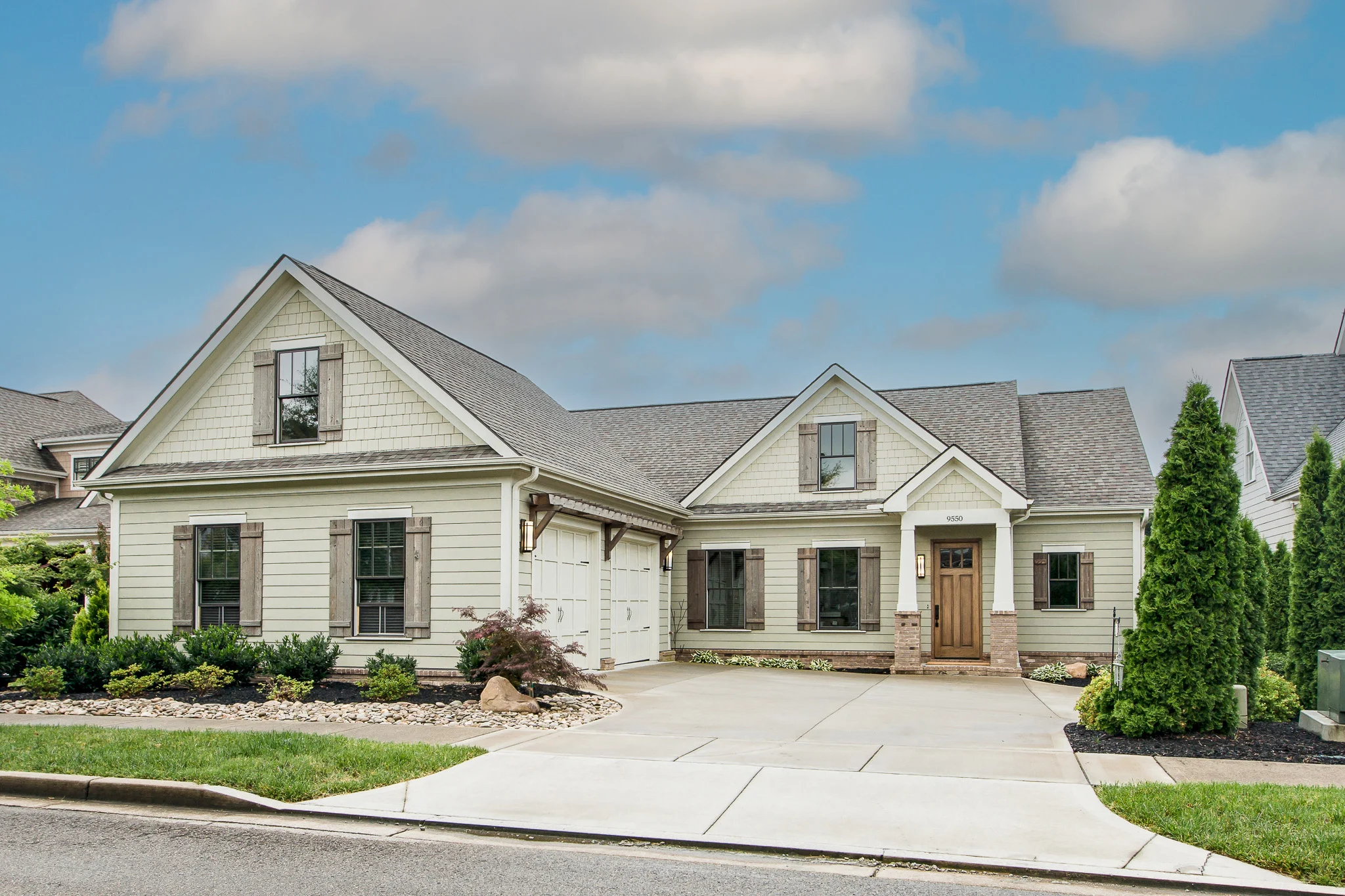 Front of Rockport Gray Farmhouse with shingled gables, cedar shutters and a stained wood front door, by Mike Stevens Homes