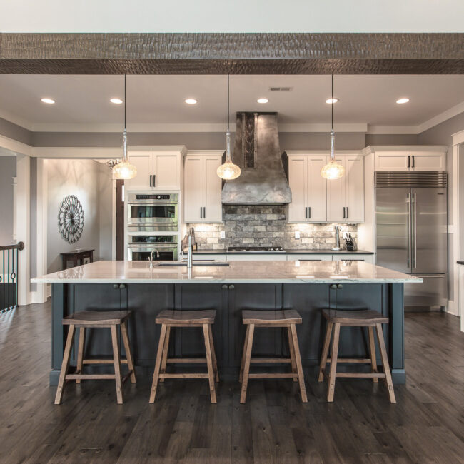 Dark kitchen island with wood stools in Rockport Gray Farmhouse, a custom home by Mike Stevens Homes