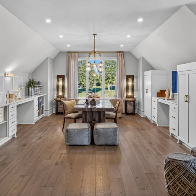 Sunset Heights upstairs bonus room with built-in white desks and shelves, a central table with stools and a brass chandelier