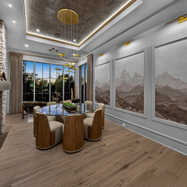 Sunset Heights dining room with mountain murals on the right wall, a round table and a stone fireplace, seen from the nook