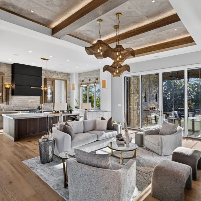 Sunset Heights great room with gray sofas, a beamed parquet ceiling, an island kitchen behind and glass doors to the porch