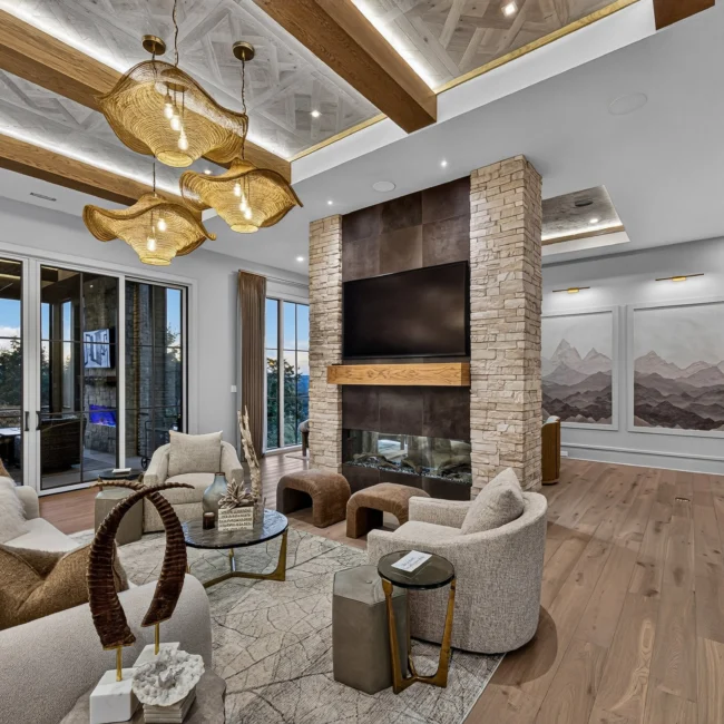 Sunset Heights great room with beige sofas, woven pendants on a beamed ceiling, a stone fireplace and a wall of sliding doors